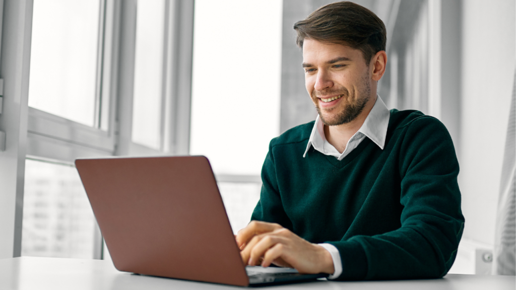 Person working on a laptop at a desk in a bright, modern workspace.